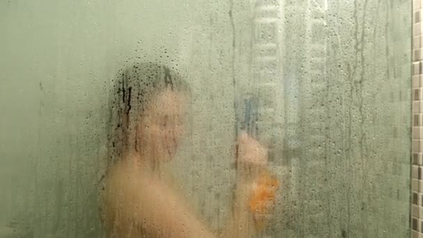 Kvinna tar dusch utsikt genom dimmiga glas — Stockvideo