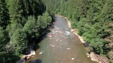 İnsanlar yaz güneşli bir günde dağda rafting yapıyor.