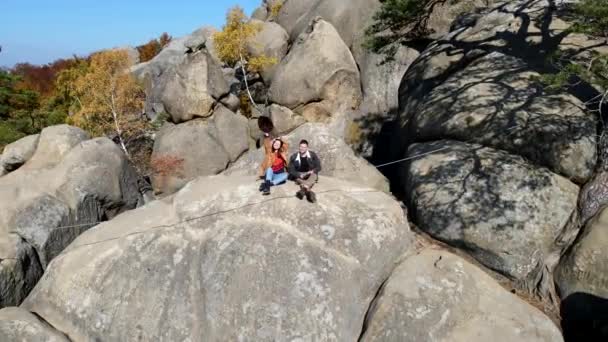 Couple resting at the top of the rock enjoying view of autumn forest — 비디오