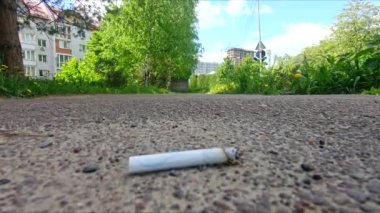 Yerde sigara boğası var. Yoldan geçen adam.