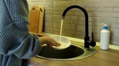 Mutfak lavabosundaki kadın tabağını kapat.