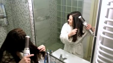 Mutlu kadın banyoda aynanın önünde saç kurutma makinesi ile şarkı söylüyor.