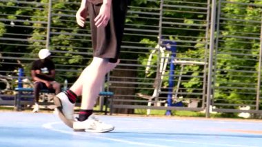 Erkek bacaklarının açık havada basketbol oynadığı bir video.