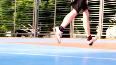 Erkek bacaklarının açık havada basketbol oynadığı bir video.