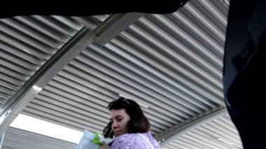 woman put bags with groceries in car trunk view from inside