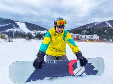 Snowboard 'lu bir adam Kar Tepesi Spor aktivitelerinde oturuyor