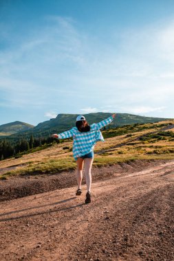 Kadın dağların tepesinde gün batımının keyfini çıkarıyor.