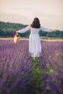 Lavanta tarlasında gün batımında beyaz elbiseli muhteşem bir kadın.