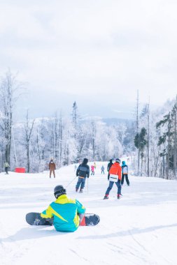 Tepede oturan adam manzaranın tadını çıkarıyor. Snowboard. Kış sporları. Boşluğu kopyala