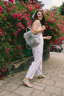 Genç, güzel, gülümseyen bir kadın, kırmızı güllerin yanında.