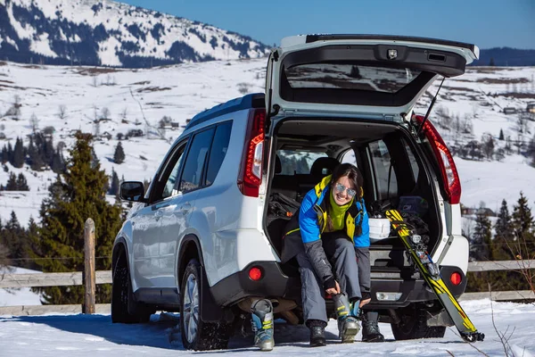 Kadın bagajda kayak yapmak için bot değiştiriyor. Güneşli bir gün. Kış yolculuğu