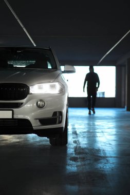 Park yerinin altındaki otoparka doğru yürüyen bir adam.