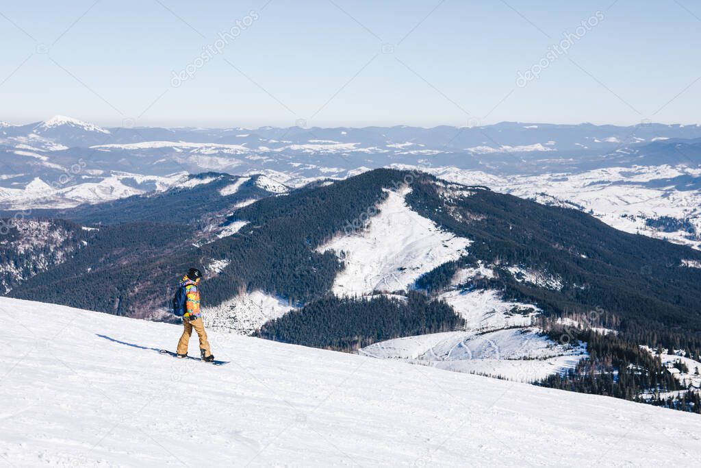 man snowboarder at the top of the slope. beautiful winter mountains. winter vacation. copy space. extreme sport