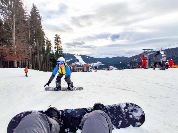 Man zittend op besneeuwde heuvel met snowboard gelukkige vrouw voor — Stockfoto