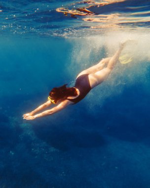 Suyun altında yüzen seksi bir kadın. Yüzgeçli bir yüzgeç maskesiyle yaz tatili.