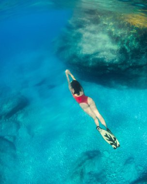 Suyun altında yüzen seksi bir kadın. Yüzgeçli bir yüzgeç maskesiyle yaz tatili.