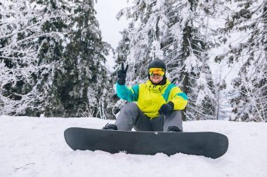Snowboard 'la karlı zeminde oturan adam. kış sporu aktiviteleri