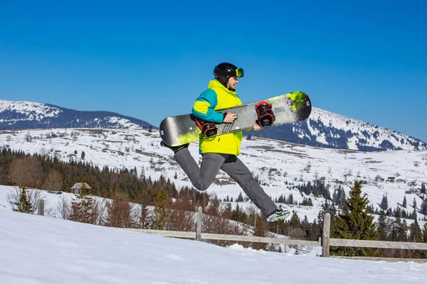 Άνθρωπος Άλμα Snowboard Στα Χέρια Βουνά Στο Παρασκήνιο Ηλιόλουστη Μέρα — Φωτογραφία Αρχείου
