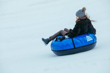 LVIV, UKRAINE - 7 Ocak 2019: şişme borularla karlı tepenin yanından kaymak. Kış eğlenceleri. hız hareketi