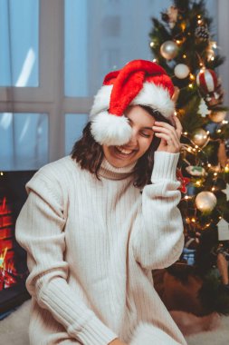 Lviv, Ukrayna - 15 Aralık 2021: Genç güzel bir kadın noel ağacının yanında oturmuş kahve içiyor fotokopi uzayı