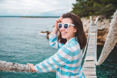 Kadın yaz mevsiminde asma köprüyü geçiyor.