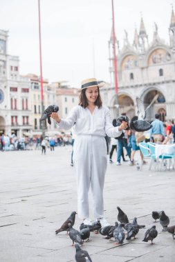 Beyaz şapkalı kadın Venice City Meydanı San Marco 'da güvercinlerle eğleniyor.
