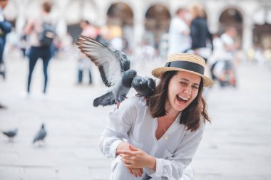 Beyaz şapkalı kadın Venice City Meydanı San Marco 'da güvercinlerle eğleniyor.