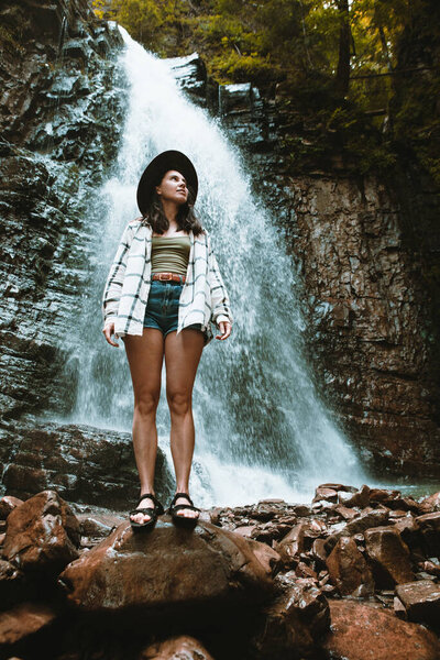 woman in brown hat enjoying view of waterfall hiking travel concept