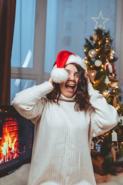 Lviv, Ukrayna - 15 Aralık 2021: Genç güzel bir kadın noel ağacının yanında oturmuş kahve içiyor fotokopi uzayı