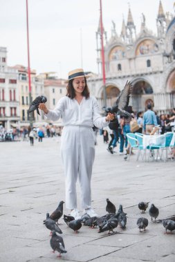 Beyaz şapkalı kadın Venice City Meydanı San Marco 'da güvercinlerle eğleniyor.
