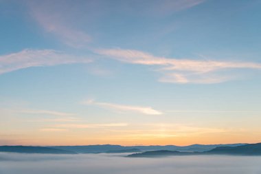 Dağların tepesindeki güneşin doğuşunun manzarası.