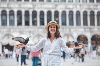 Beyaz şapkalı kadın Venice City Meydanı San Marco 'da güvercinlerle eğleniyor.