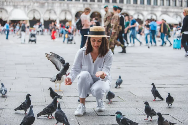 Beyaz şapkalı kadın Venice City Meydanı San Marco 'da güvercinlerle eğleniyor.