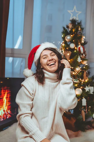 Lviv, Oekraïne - 15 december 2021: jonge mooie vrouw zit bij kerstboom koffie te drinken — Stockfoto