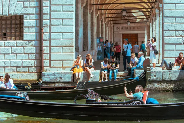 Venice, Italy - May 25, 2019: people resting at city quay looking at gondolas — Stock Photo, Image