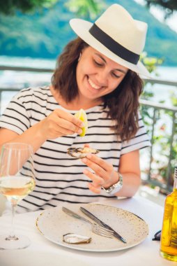 Güneşli yaz havasında açık hava restoranında istiridye yiyen bir kadın. Yaşam biçimi