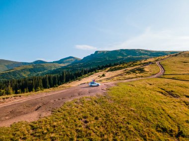 Karpatlar 'ın Ukrayna dağlarının manzarasını seyreden çift arazi aracının çatısında oturuyor.