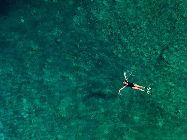 overhead view of woman floating on back in clear sea water greece vacation