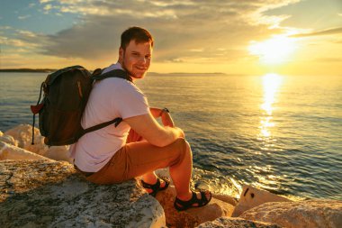 Sırt çantalı bir adam denizde günbatımının tadını çıkarıyor. kopyalama alanı. yaz tatili