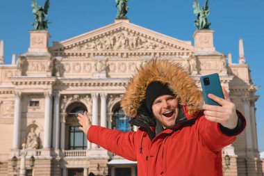 Gülümseyen adam Lviv City Ukrayna 'nın opera binasının önünde selfie çekiyor.
