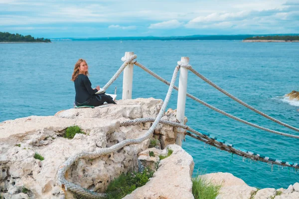 Kenarda Oturan Kadın Deniz Manzaralı Asma Köprü Resmi Çiziyor — Stok fotoğraf