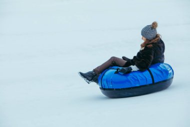 LVIV, UKRAINE - 7 Ocak 2019: şişme borularla karlı tepenin yanından kaymak. Kış eğlenceleri. hız hareketi