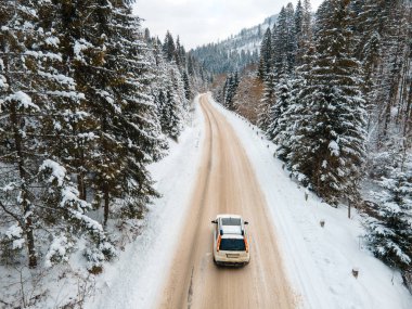 Kış mevsiminde karlı yolda arabanın hava görüntüsü.