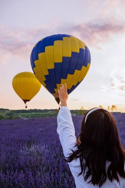 Kvinna stående på lavendelfält tittar på luftballonger med korg — Stockfoto