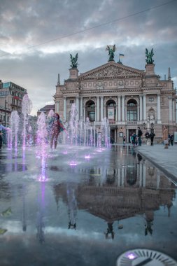 Lviv, Ukrayna - 14 Mayıs 2021: İnsanlar opera binası çeşmesinin önünde şehir meydanından yürüyorlar
