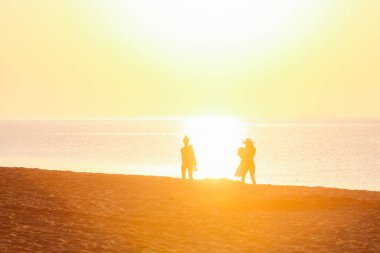 Gün batımında kumsalda yürüyen bir grup arkadaş. yaz tatili