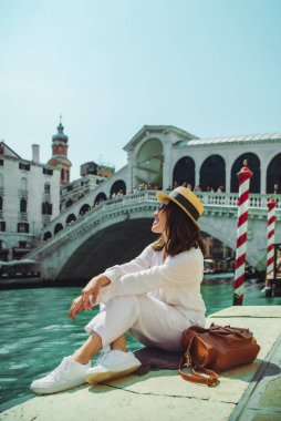 Venedik 'te rialto köprüsünün yanında oturan kadın gondollu Grand Canal' a bakıyor.