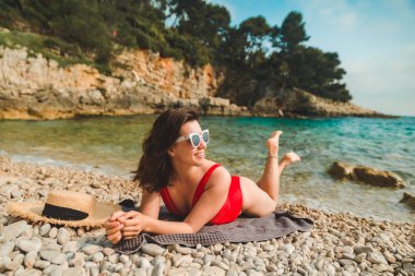 Kadın deniz sahilinde battaniyeye uzanmış fotokopi çekiyordu.