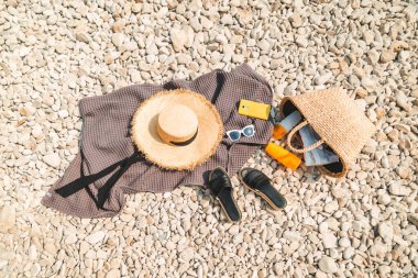 Plaj eşyaları battaniyesi, güneş korumalı krem hasır şapka ve çanta.