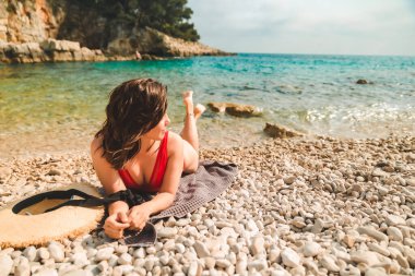 Kadın deniz sahilinde battaniyeye uzanmış fotokopi çekiyordu.